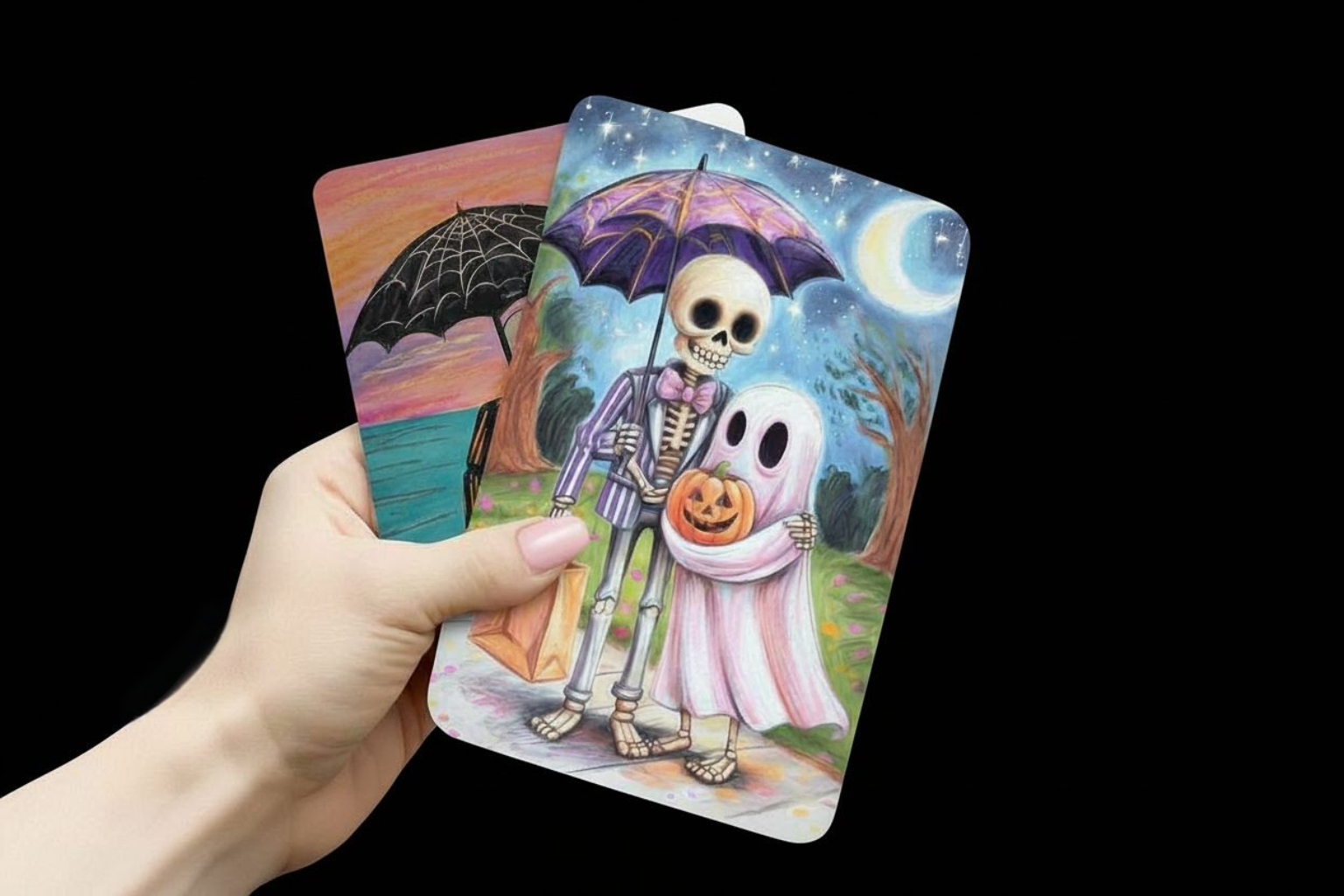 Hand holding tarot cards with Halloween-themed illustrations of a skeleton and ghost couple, card stock, Halloween, seasonal, collection, pink, skeleton family